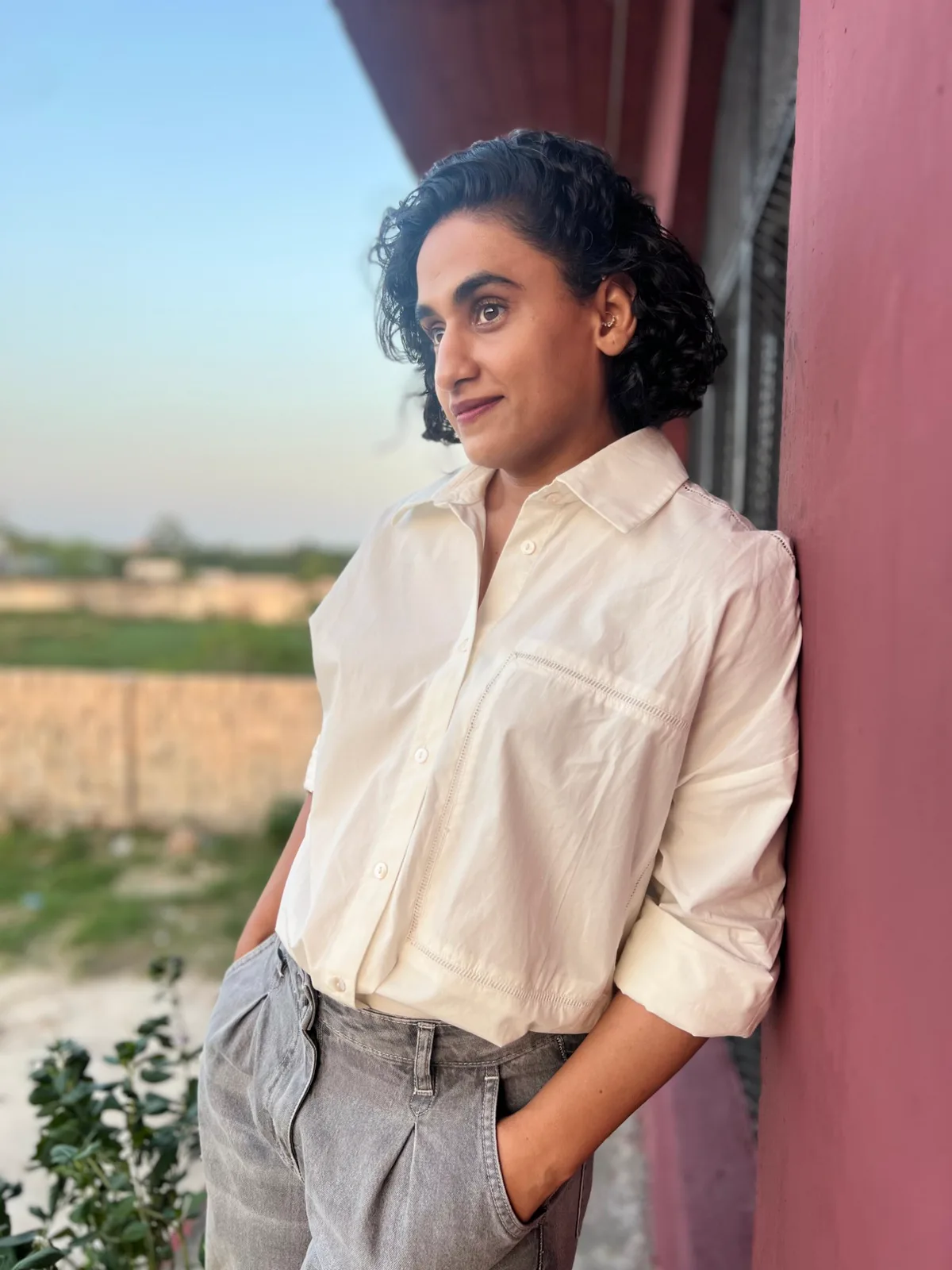 Portrait of the Quadko founder in a white shirt, leaning against a rose-coloured wall at dusk in Islamabad